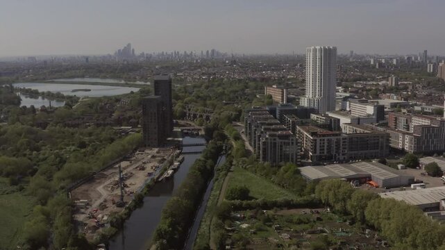 Aerial of Tottenham Hale residential housing with Tottenham Hotspur Stadium in the background and a white and red London tube train in the foreground