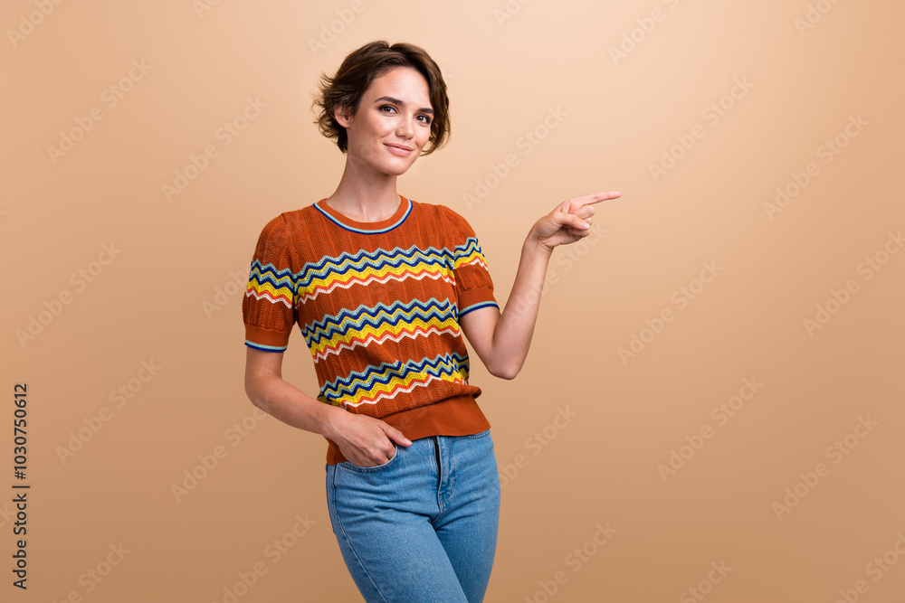 Wall mural Portrait of lovely nice person put hand pocket direct finger empty space offer isolated on beige color background