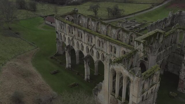 Drone shot of Rievaulx Abbey, showcasing the historical ruins surrounded by green fields and hills in North Yorkshire, England.