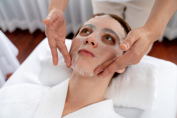 Serene modern daylight ambiance of spa salon, woman customer indulges in rejuvenating with facial skincare mask. Facial skin treatment and beauty cosmetology procedure for face. Quiescent