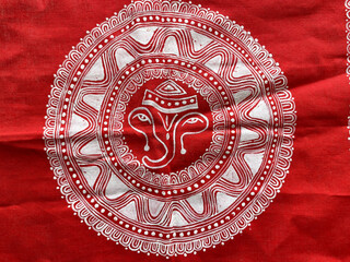 Aipan art on red cotton fabric showcases the traditional  Ganpati Kumaoni craft through intricate white rice paste patterns
