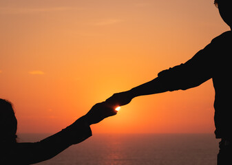 Close up of diverse couple holding hands at beach during sunset. lifestyle, free time and vacation.
