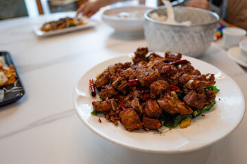 fried sticky ribs marinated in soy sauce and ginger sprinkled on white dish on marble table, chineese style.