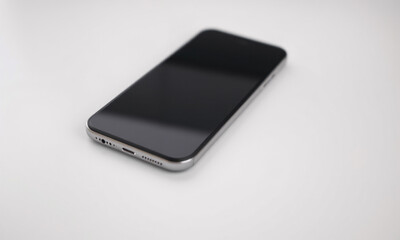 a modern smartphone lying flat on a smooth white surface