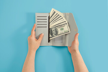 Hands holding wallet with hundreds of dollars in cash on isolated background