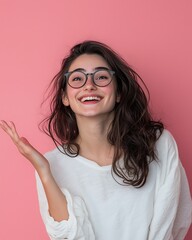 Obraz premium A smiling young woman in glasses, playfully gesturing with her hand against a vibrant pink background.