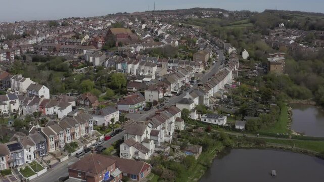 Drone shot of residential houses and streets in Hastings with green surroundings on a clear day in England, UK.