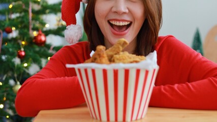 Joyful Asian woman Holding fried chicken and bucket, person with christmas tree and gifts