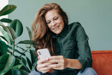 Happy smiling woman using mobile phone for online communication.
