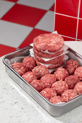 Semi finished patties and meatballs in a metal tray