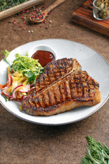 Portion of grilled beef t bone steak with salad
