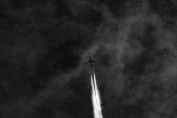 Airplane in the blue sky with white clouds and contrail.