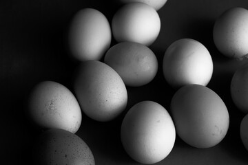 Group of many farm fresh free range organic chicken eggs for healthy breakfast food closeup in moody black and white image.