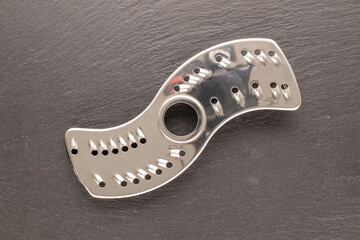 One metal mixer knife on slate stone, macro, top view.