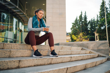 Young sporty woman using smartphone after training outdoors