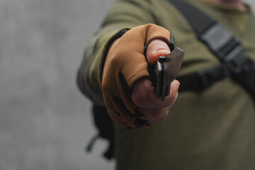 Male military man holding a tactical knife in his hand. Soldier with tactical backpack and brown gloves.