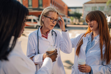Female doctors taking coffee break outside hospital building