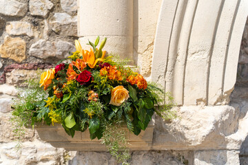 Colorful flower arrangement with lilies and roses with old stone walls in the background