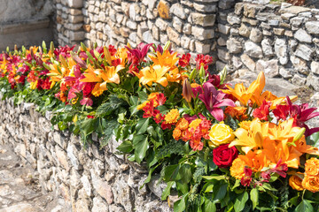 Colorful flower arrangement with lilies and roses with old stone walls in the background