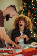 Young couple wrapping christmas presents having fun