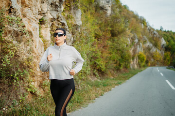 Young caucasian woman running or jogging on the country road	