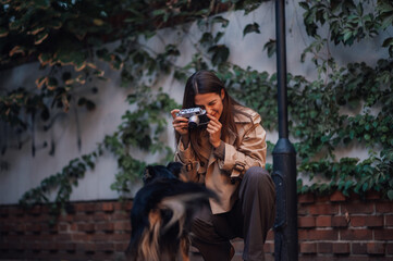 Woman crouching and taking photo with vintage camera of dog