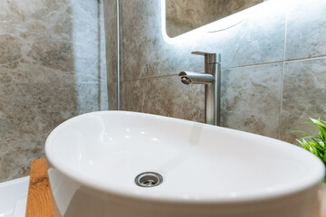 The modern bathroom sink features an elegant faucet and a chic mirror, enhancing everyday use and the overall design, adding style and practicality to this essential space