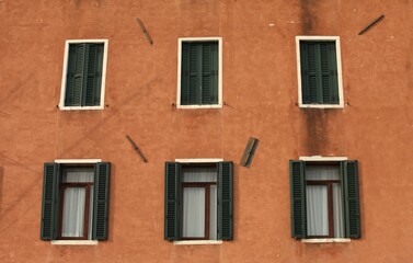 Obraz premium Green windows on an orange building, three open in the upper row and three open in the lower part