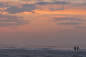 Fototapeta premium Avalon, New Jersey - Peaceful Sunrise at this beach on the New Jersey shore with two silhouettes of people watching the sun come out of the Atlantic Ocean
