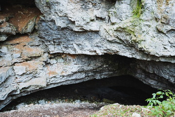 Deep within the steep cliffside lies a small, mysterious cave that formed over countless years through the relentless processes of natures erosion and various geological forces at work