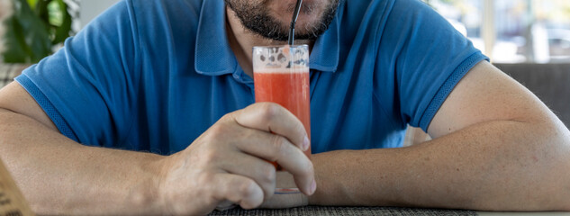 A man is drinking a glass of red juice