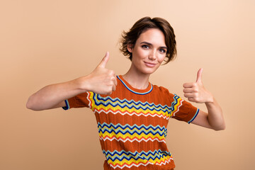 Portrait of lovely positive person arms fingers demonstrate thumb up gesture isolated on beige...