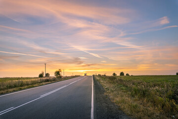 A long road with a sunset in the background