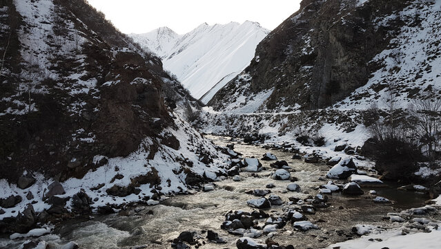 Mountain river among snowy slopes