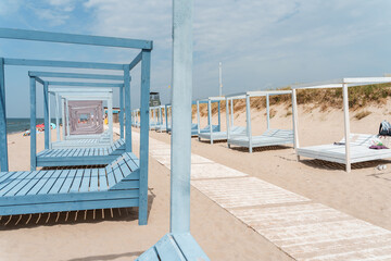 Beautiful beach in Yantarny with blue wooden sun beds and blue sky, Baltic Sea. Yantarny,...