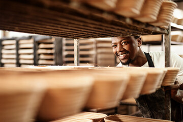 Happy, black man and bakery with trolley for pastry production, bread or rolls at factory. Young African, male person or baker with smile for stock, inventory or handmade produce at storage warehouse