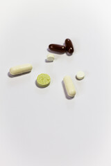 Close-up of pills of different shapes and colors on a white background. Do not self-medicate.