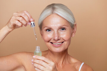 Beauty skincare fashion portrait of a mature senior woman with a grey silver hair and glowing skin...