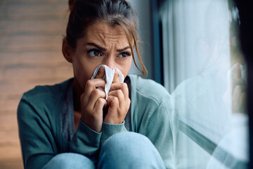 Woman with cold and flu virus blowing her nose.