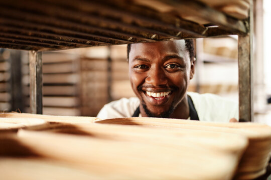 Happy black man, portrait or bakery with trolley for pastry production, bread or rolls at factory. Young African, male person or baker with smile for stock, inventory or handmade produce at warehouse