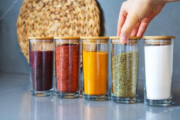 Cropped hand holding jar of spices on kitchen.