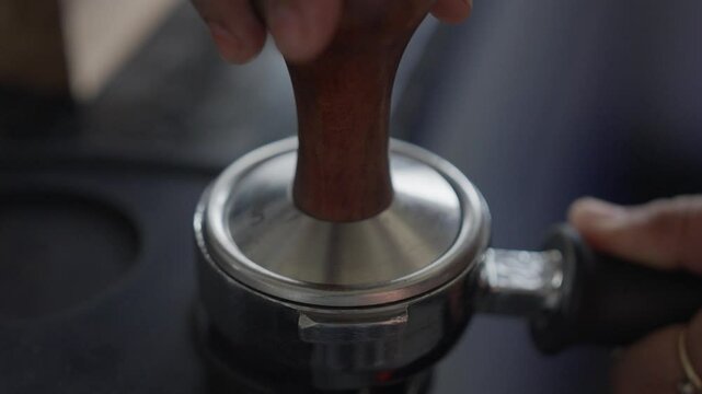 Closeup of a footage of a hand of barista tamping coffee in portafilter