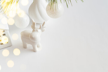 Christmas decoration in home interior, scandinavian style. Christmas deer, branches in a vase on a white table