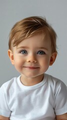 Portrait of a smiling toddler in a white t-shirt on a neutral background.