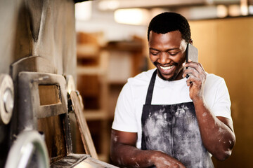 Happy, black man and bakery with phone call for communication or conversation at factory. Young African, male person or baker with smile on mobile smartphone for discussion on pastry production