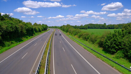 Fototapeta premium Autobahn, expressway, motorway in Germany in summer. View from the bridge. Beautiful blue sky with white clouds.