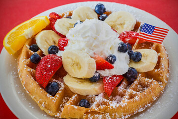 Belgian waffles with banana, fresh berries, and whipped cream.  