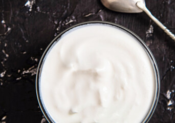 Bowl of tasty fresh sour cream on a dark background