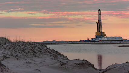 Drilling oil and gas wells in desert terrain. Sand hills, sparse vegetation. Beautiful sky. Infrastructure of the drilling rig