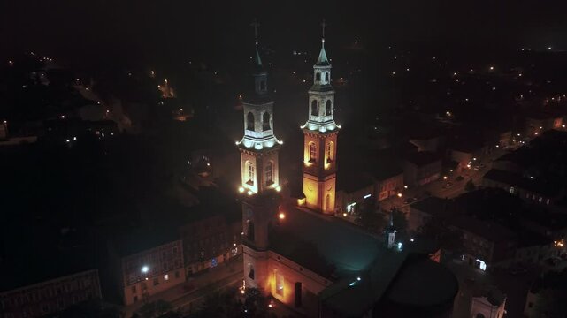 Nocna orbita wok&oacute;ł Bazyliki NMP i Św. Bartłomieja w Piekarach Śląskich &ndash; podświetlone wieże na tle miasta